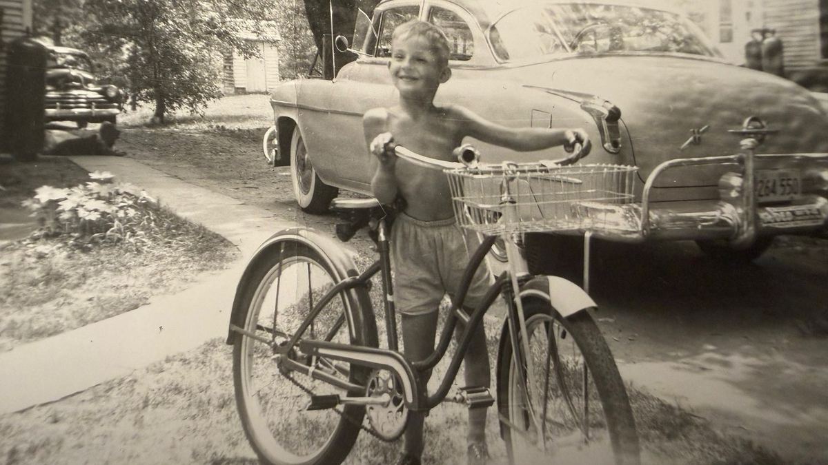Joseph with a new bicycle beside the family car